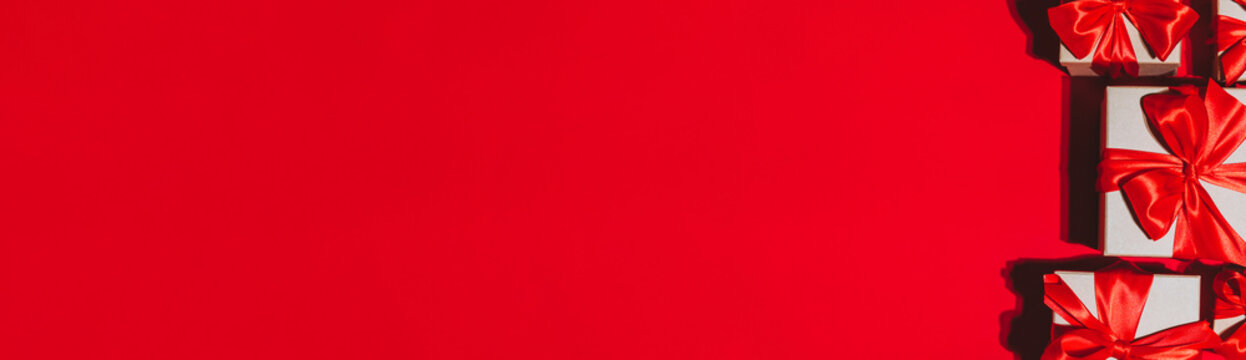 Gorgeous festive Christmas banner or header, holiday presents on red background. Christmas gift boxes on red. Holiday season, New Year. Copy space for text.