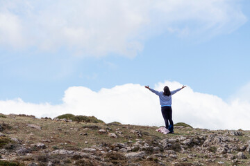 Mujer levantando los brazos hacia el cielo en un paisaje rocoso de montaña