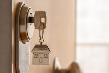 CLOSE UP OF KEY AND HOUSE KEYCHAIN ​​IN HIGH SECURITY DOOR LOCK. HOME INSURANCE CONCEPT. COPY...