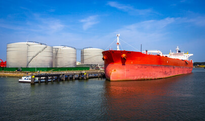 Crude oil tanker docked at a oil storage silo terminal in the port. - 537081115