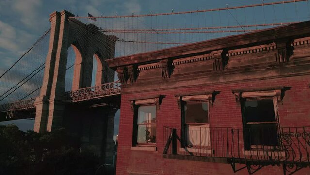 rising alongside old house in Dumbo view of Brooklyn Bridge at sunset