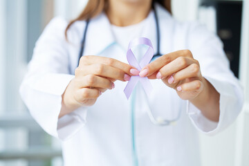 Woman doctor white uniform hold purple ribbon on hand symbol of Pancreatic cancer awareness