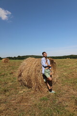 guy resting in a field on a haystack