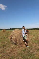 guy resting in a field on a haystack