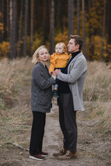 Fototapeta premium Happy caucasian couple with little baby boy. Parents and son having fun together among autumn leaves. Mother and father playing with toddler outdoors. Family, parenthood, childhood, happiness concept.