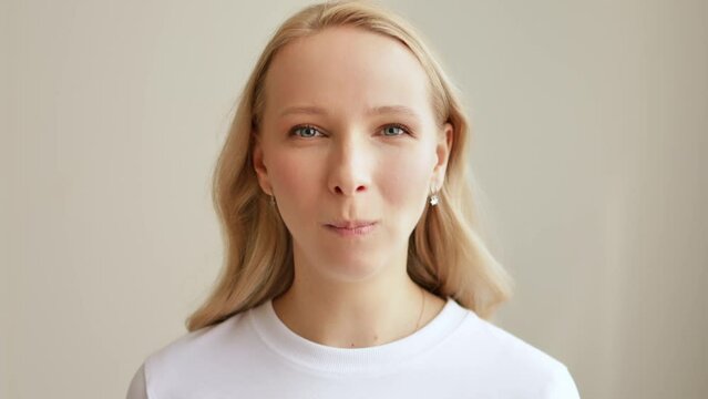 Young beautiful blonde woman eating potato chips and chews it while looking at the camera and smiling. Fast and junk food.