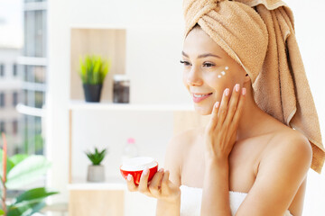Obraz na płótnie Canvas Beautiful woman applying moisturizer cream on her face.