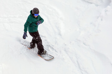 Fototapeta na wymiar snowboarder in equipment descends mountain slope, active recreation in winter, extreme winter recreation