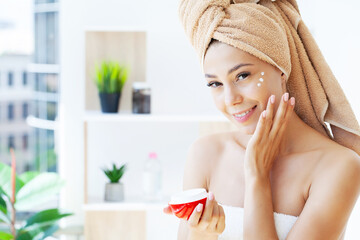 Obraz na płótnie Canvas Beautiful woman applying moisturizer cream on her face.