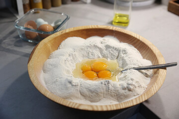 Flour and eggs in wooden bowl with spoon dough components home backery