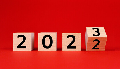 Wooden cubes with numbers 2023 and 2022 on a red background. Symbol of the old 2022 and the new year 2023