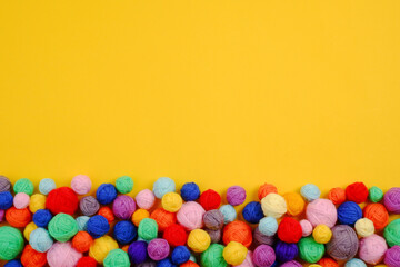 Background of colorful bright balls of yarn for knitting or crocheting on a yellow background.The concept of manual labor, crafts, hobbies, a banner for the sale of yarn.Copyspace.