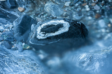 Gray stone with a white quartz ring in a mountain stream