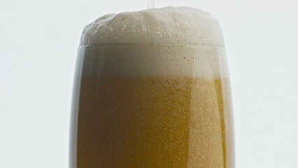 Craft beverage pouring transparent glass closeup. Stream making foam drink
