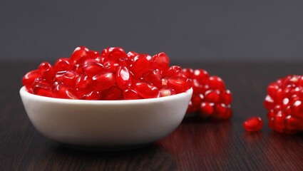 Pomegranate in a white bowl on a dark background. Shallow depth of field