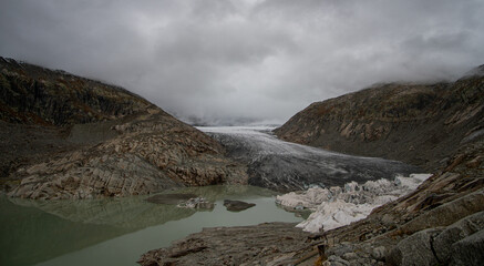 Rhone glacier and lake in the Swiss alps on a cloudy day in autumn