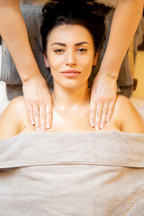 Portrait of beautiful adult smiling woman lying relaxed on a couch during professional relaxation massage, view from above. Woman receives spa treatment in beauty salon