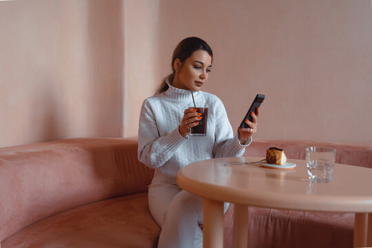 Caucasian beautiful woman at videoconference online meeting while drinking special coffee in modern stylish cafe. Concept of remote work and study.