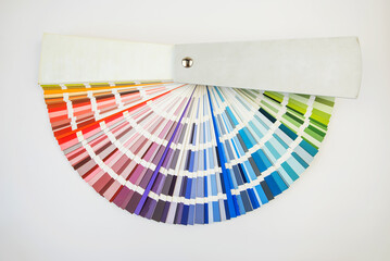 Color guide close up. Assortment of colors for design. Colors palette fan on white concrete wall background. Graphic designer chooses colors from the color palette guide.