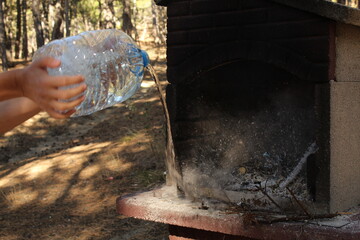 A man hand extinguished the fire in a grill with a bottle of water. Long exposure