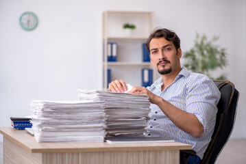 Fototapeta premium Young male employee unhappy with excessive work in the office