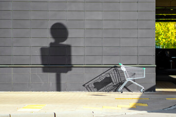 A trolley from the supermarket stands near the wall on the street