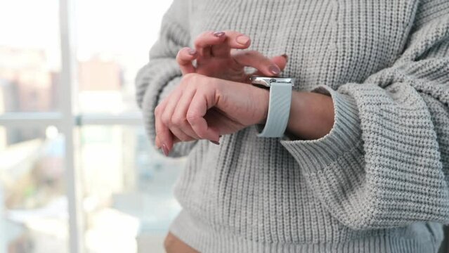 Girl using smart watch and touching screen choosing options on digital clock device. Person hands with modern gadget on wrist