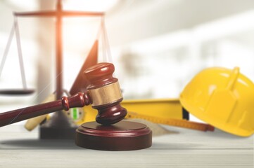 Judge's wooden hammer and worker helmet on the desk