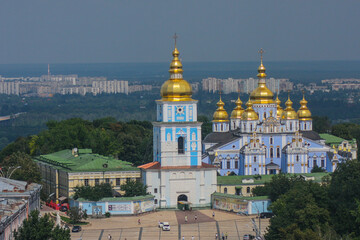 Fototapeta na wymiar Monastery and church in Kiev viewed from far, with majestic city backdrop behind. Churches in kiev, blue church with golden roof