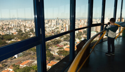 Menino em um mirante, na torre panorâmica,  observa a cidade de Curitiba, Brasil