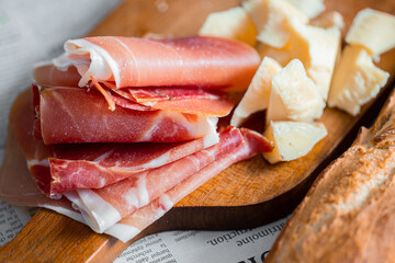 Wooden board with cheese and ham. Board with jamon and cheese. Aperitif on the board. Jamon with bruschetta and parmesan.Delicious appetizer for wine.Italian appetizer. Jamon and salami with cheese.