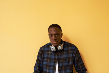 Man with headphones against yellow background.