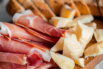 Wooden board with cheese and ham. Board with jamon and cheese. Aperitif on the board. Jamon with bruschetta and parmesan.Delicious appetizer for wine.Italian appetizer. Jamon and salami with cheese.