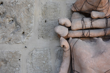 Abstract man sculpture made of stones, boards and wires uprighted in front of a wall. The person...
