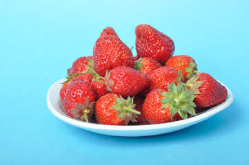 Strawberries on a plate on a blue background
