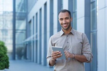 Portrait of a happy businessman outside an office building, a man in a casual shirt is looking at...