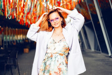 Portrait of a beautiful girl at the festival. A woman dances and smiles in a dress and glasses on a holiday against the background of confetti.