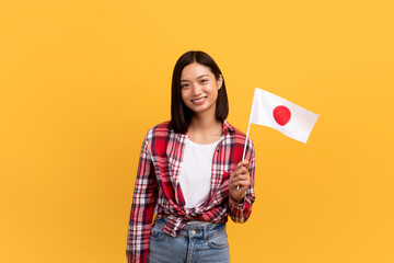 Language study and exchange student. Positive asian lady in casual holding japan flag in hand and...