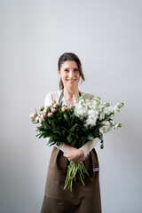 WOMAN florist EMBRACING a bunch of white and pink flowers on white background indoors