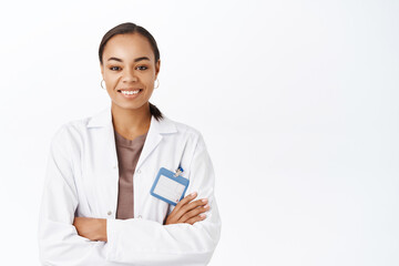 Portrait of smiling female doctor, therapist in white coat, looking confident with arms crossed. Medical healthcare concept