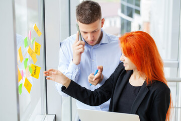 A red haired girl works together with a partner in the office on a joint project