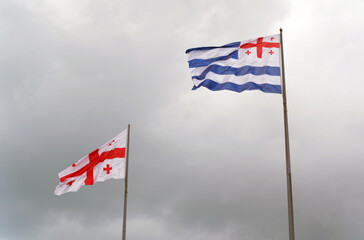 Flag of Georgia and Adjara against the sky with thunderclouds.