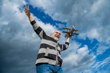 carefree senior man on sky background. senior man at retirement. senior retired man with toy plane