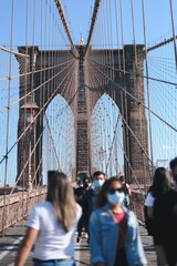 Vertical closeup shot of people walking on the Brooklyn Bridge on a sunny day in New York