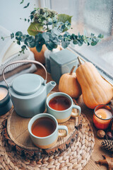 Beautiful autumn composition with burning candles and cup of tea on window sill