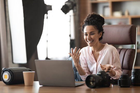 Emotional millennial woman photographer having business call, using laptop