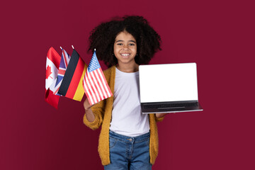 Cheerful black child holding laptop and bunch of flags