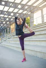 Obraz premium Young woman in concrete public stadium doing fitness stretching exercises, sports and healthy lifestyle
