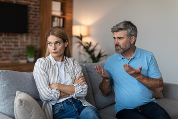 Sad offended middle aged european female ignores arguments of male during quarrel in living room...