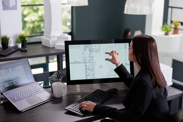 Woman working in real estate drafting software, zooming in project blueprint, designing interior in...
